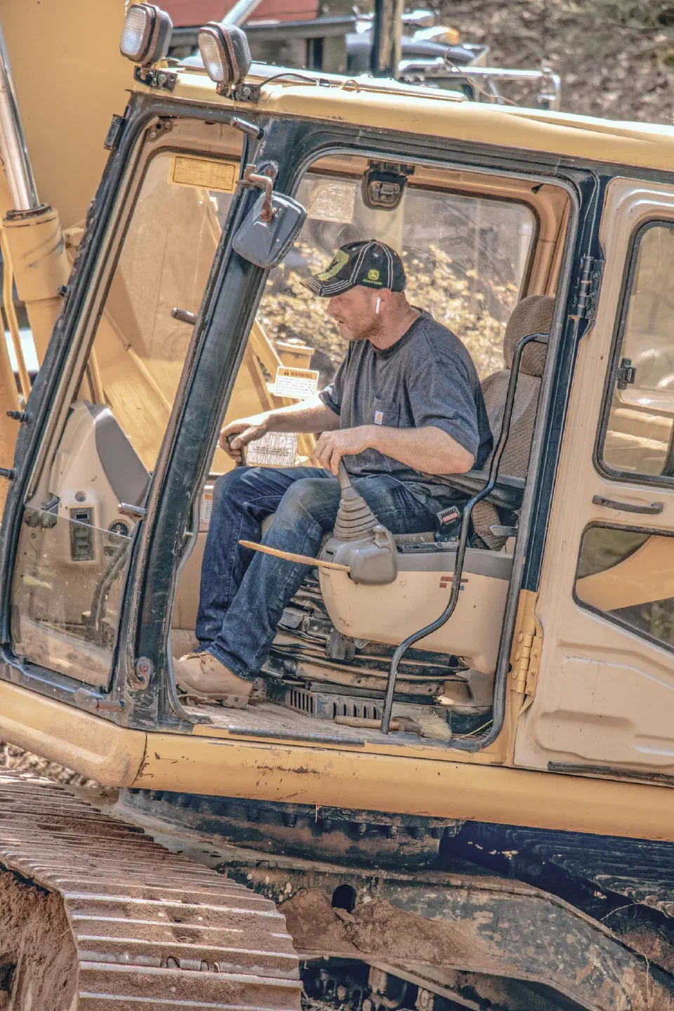 Mark Snow at the controls of an excavator, seen through the open cab door