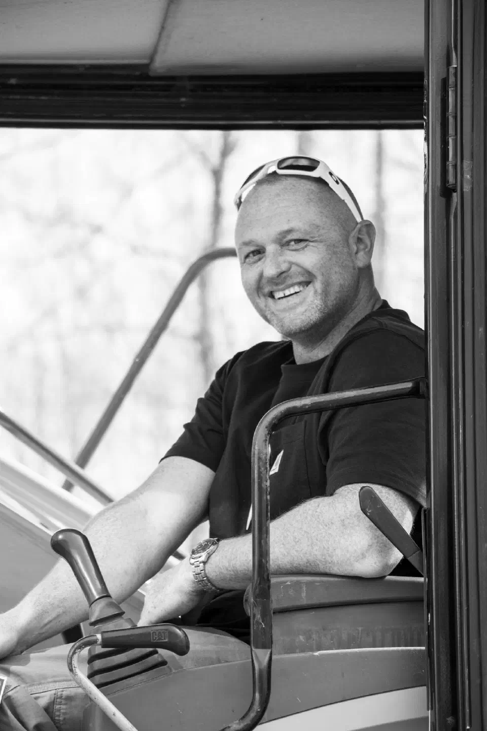 Mark Snow smiling from the cab of an excavator