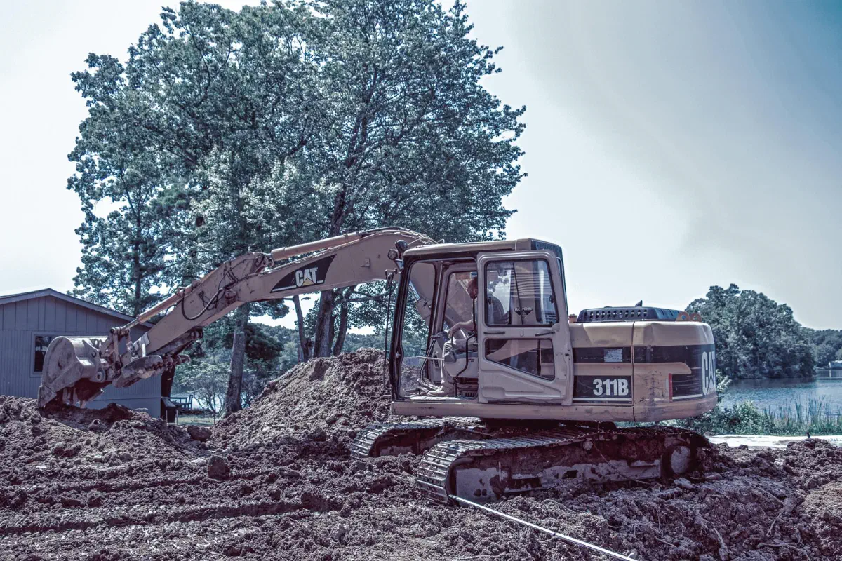 CAT excavator beside a mound of soil at a lakeside home