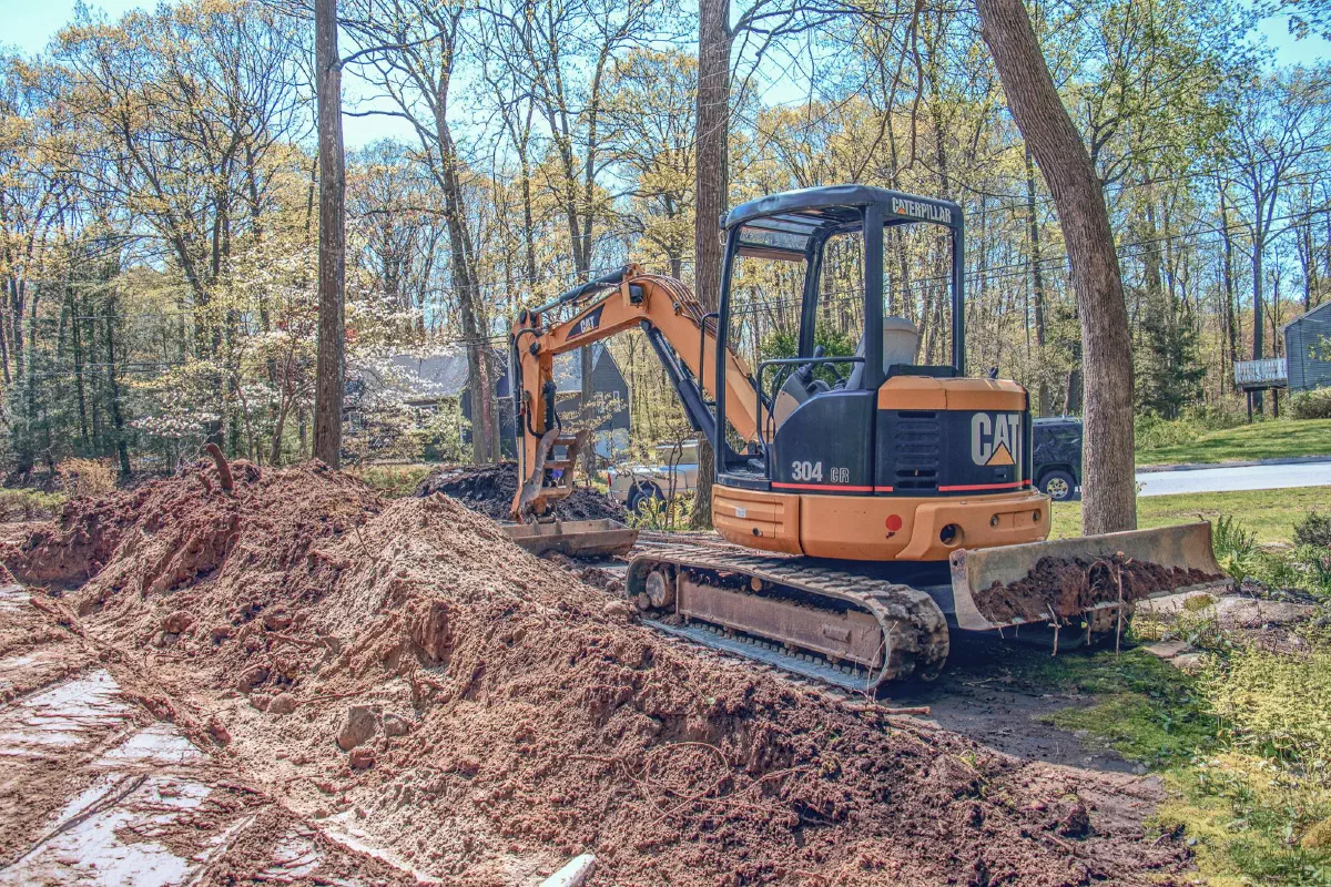 CAT mini excavator digging on a wooded lot